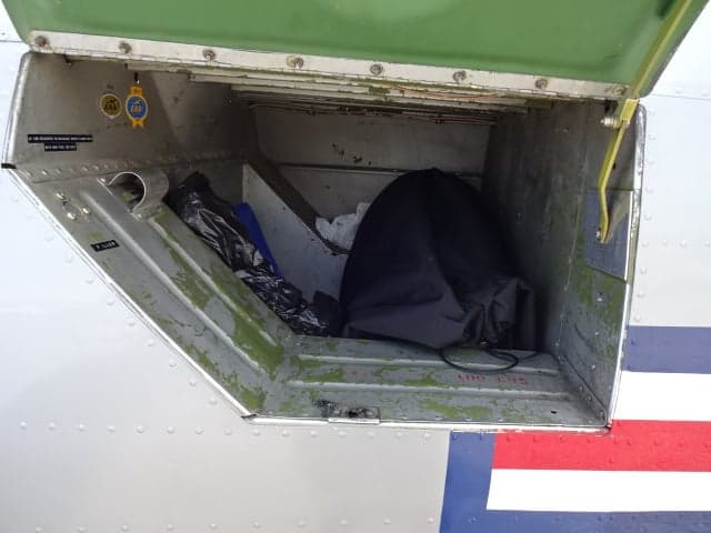 Open storage compartment on the side of the silver T-6 Texan aircraft.