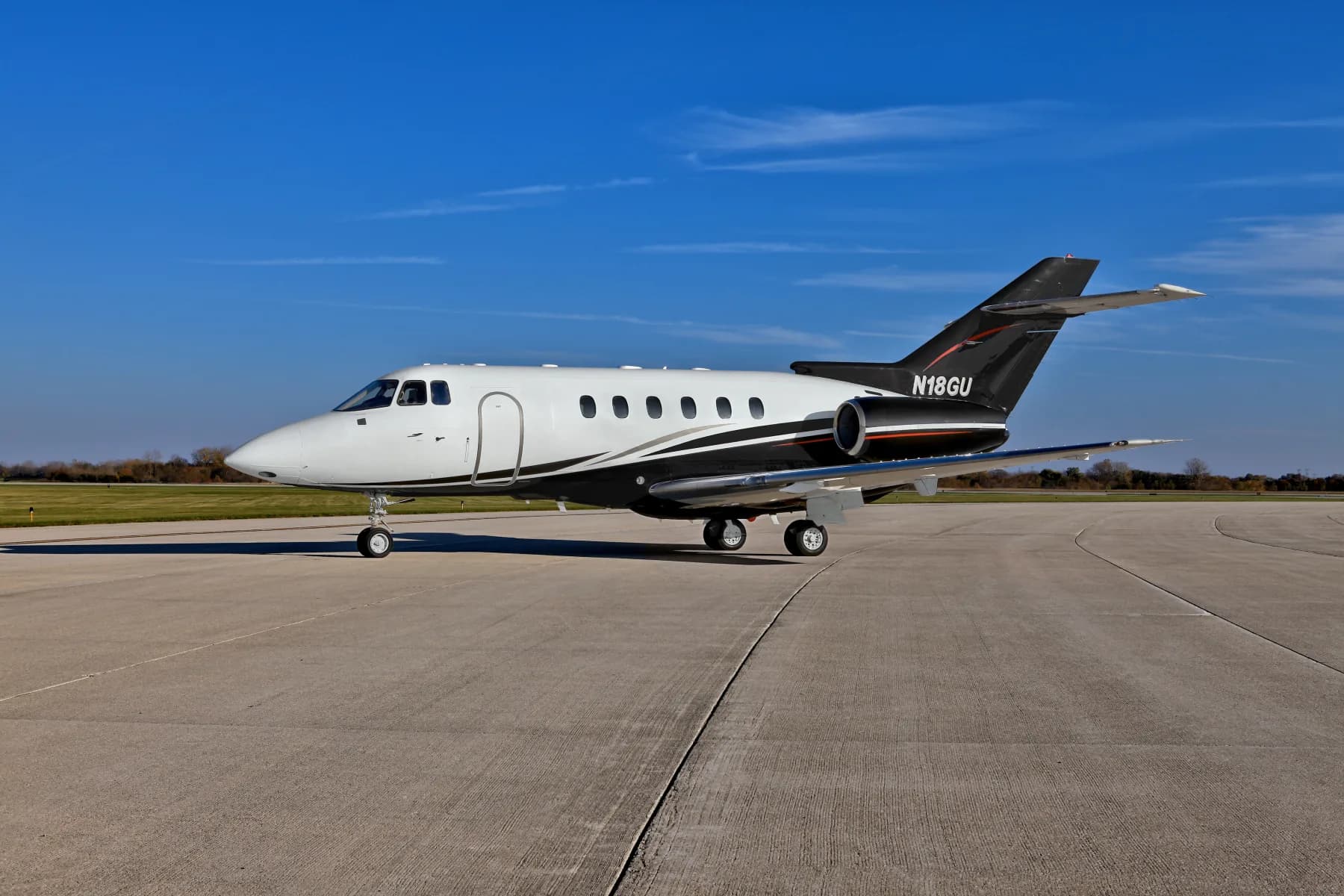 Side view of N18GU Falcon aircraft on the ground with a white and black paint scheme.