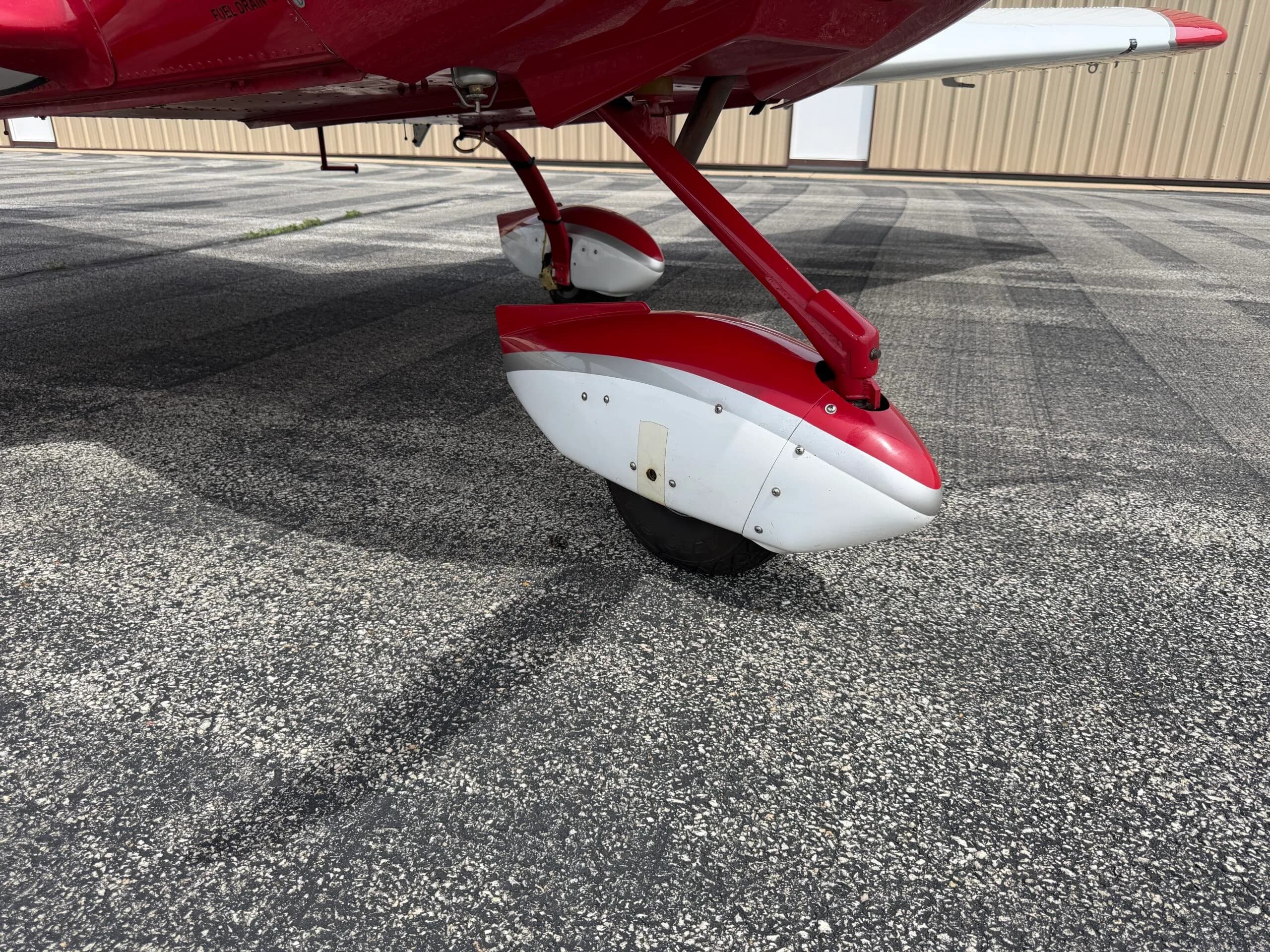 Close-up view of the red and white main landing gear of the SportCruiser aircraft on the tarmac.