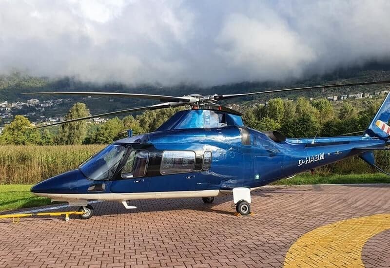 A blue AgustaWestland AW109SP helicopter, registration D-HABM, is parked on a helipad.