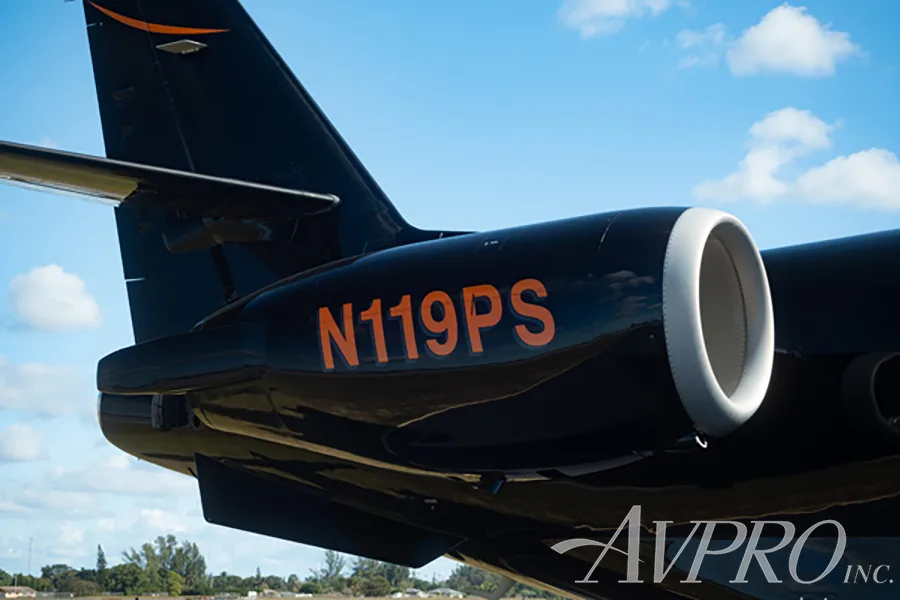 A close-up view of the rear fuselage and engine of the Gulfstream G200, showing the N119PS registration in orange on the black paint.