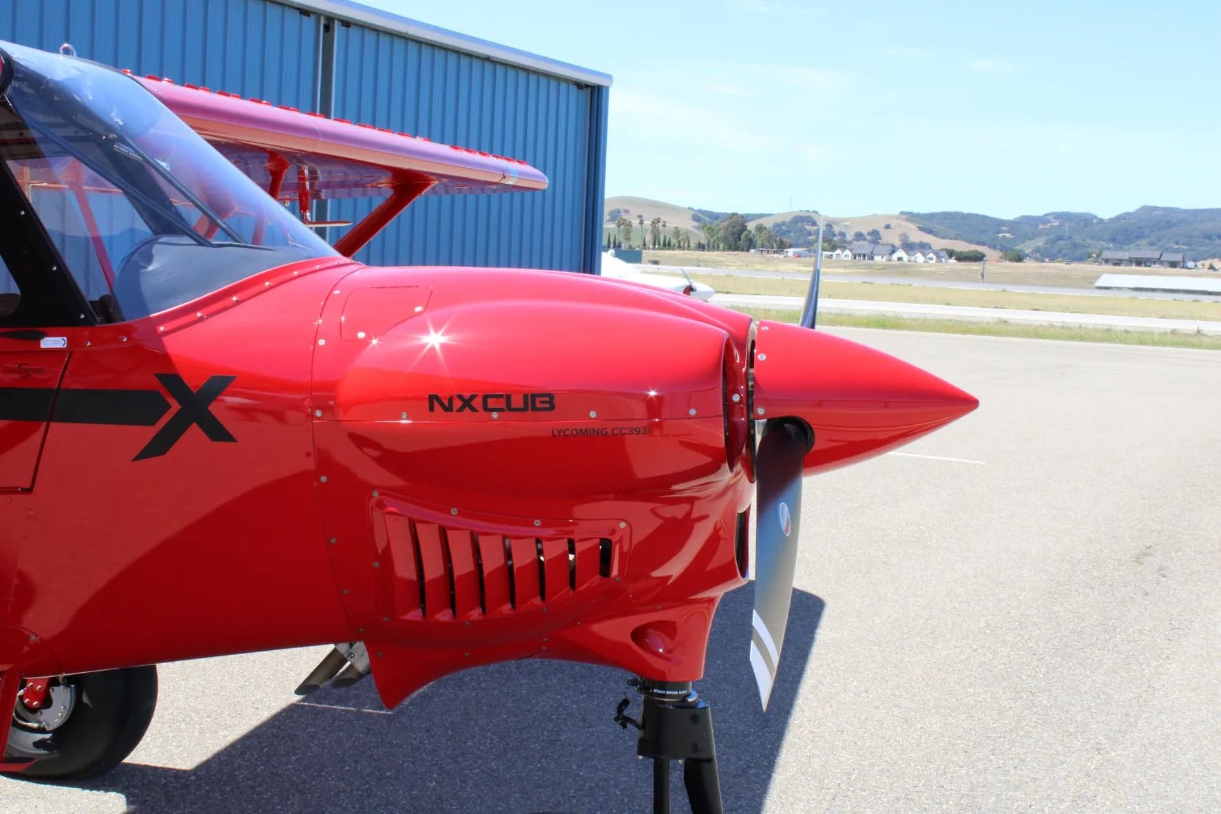 Close-up of the front of the red NX Cub aircraft on the tarmac.