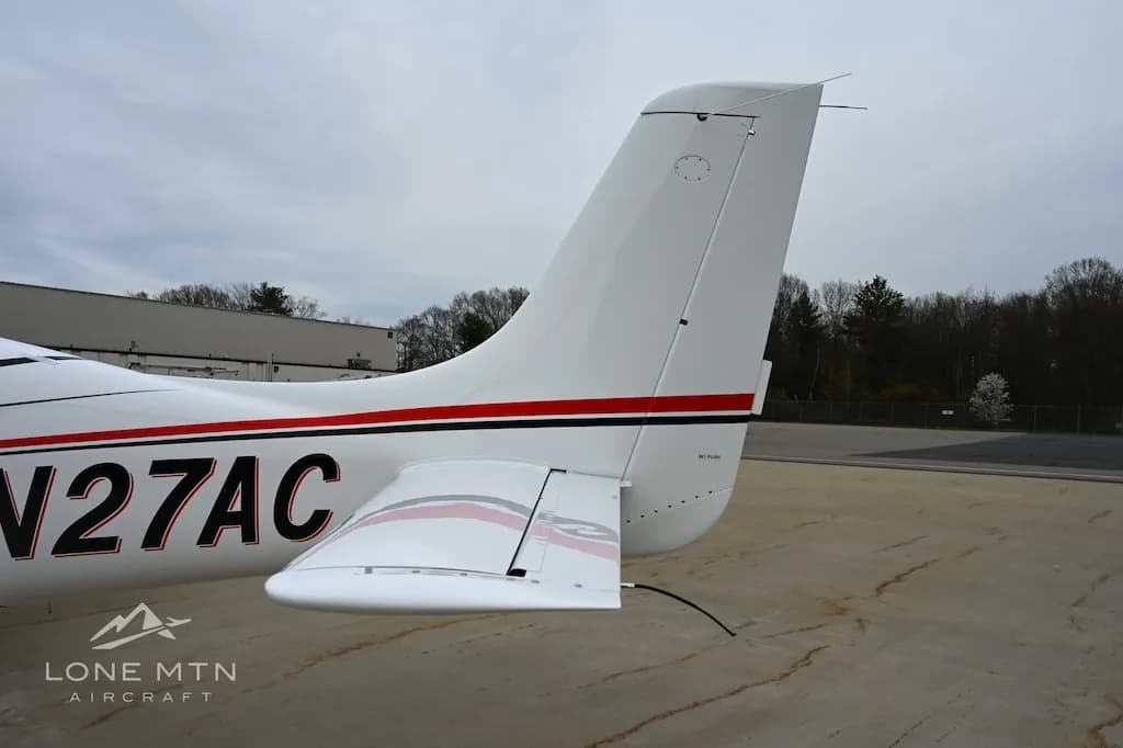 Close-up view of the tail section of a white Cirrus SR22 aircraft, tail number N27AC, showing the horizontal stabilizer.