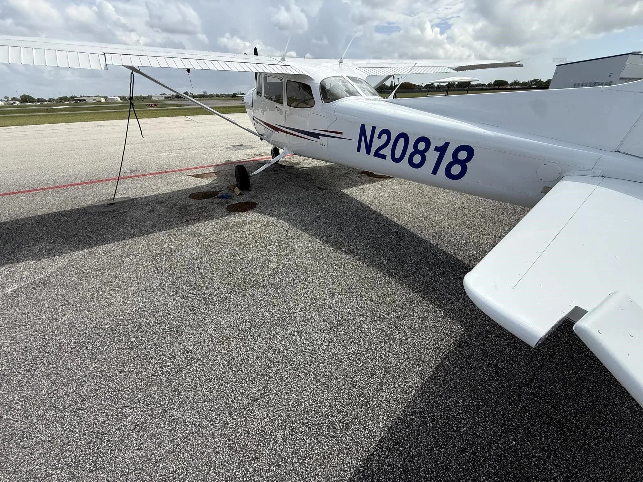A side view of the white Cessna 172 (N20818) showing the registration and red and blue stripe.
