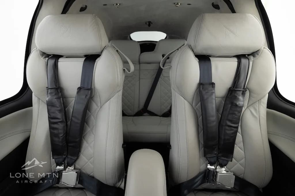 The light gray quilted leather front seats of a Cirrus SR22 aircraft cabin, looking towards the rear seats.