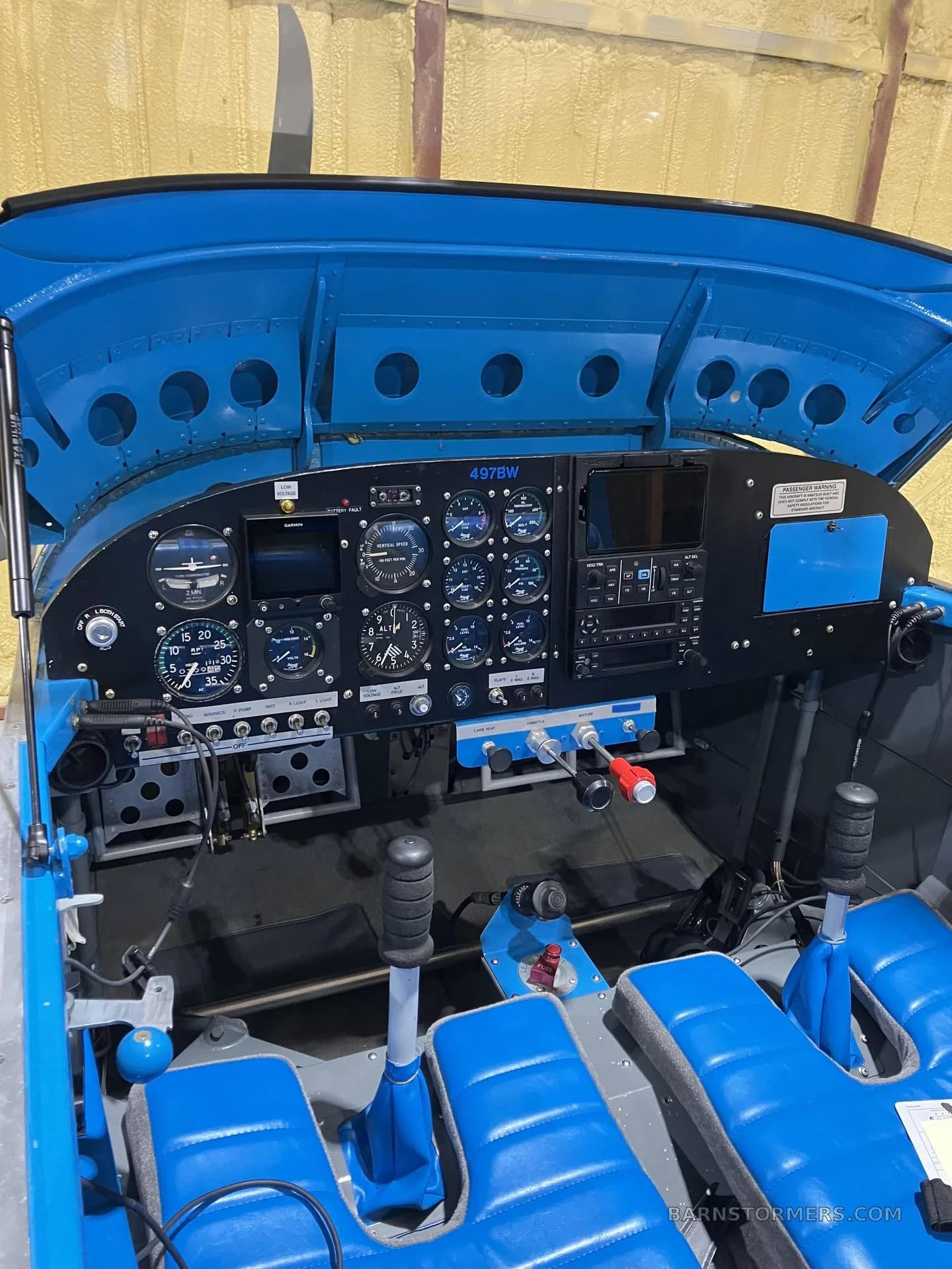 The cockpit of the experimental aircraft, showing the instrument panel with various gauges and controls, and blue seats.
