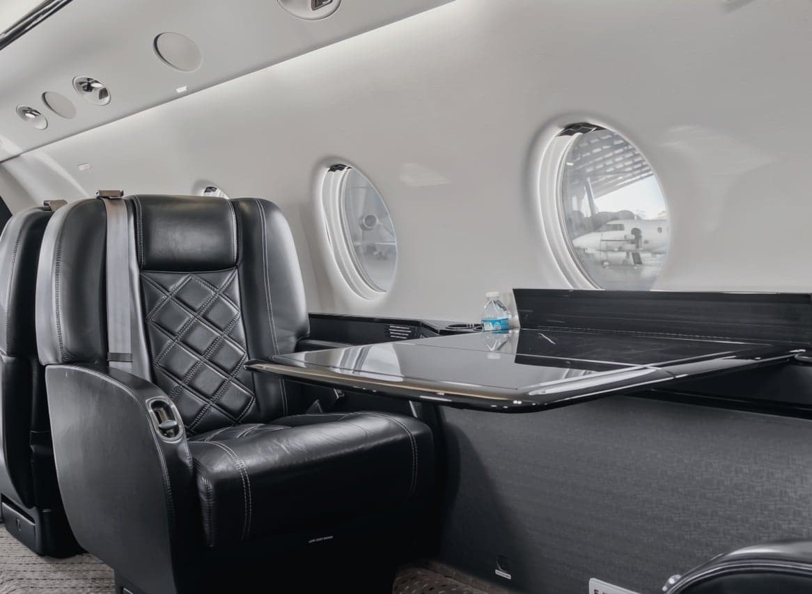 A view of the interior of the aircraft, showing the leather seats and a table.