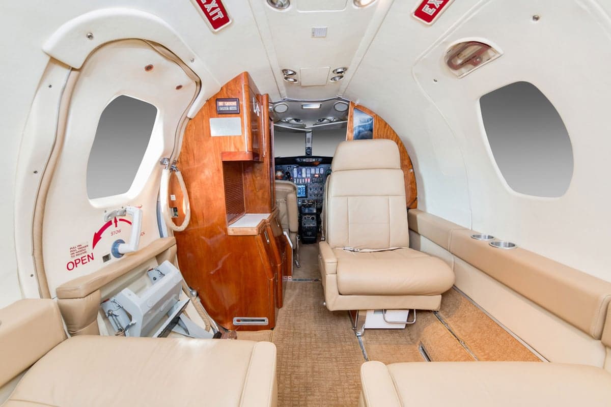 View from the aircraft cabin looking forward towards the cockpit, showing beige seats and wood cabinetry.