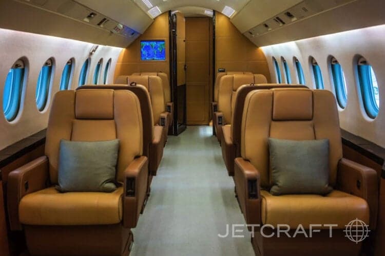 View of the aircraft cabin with leather seats and gray pillows.
