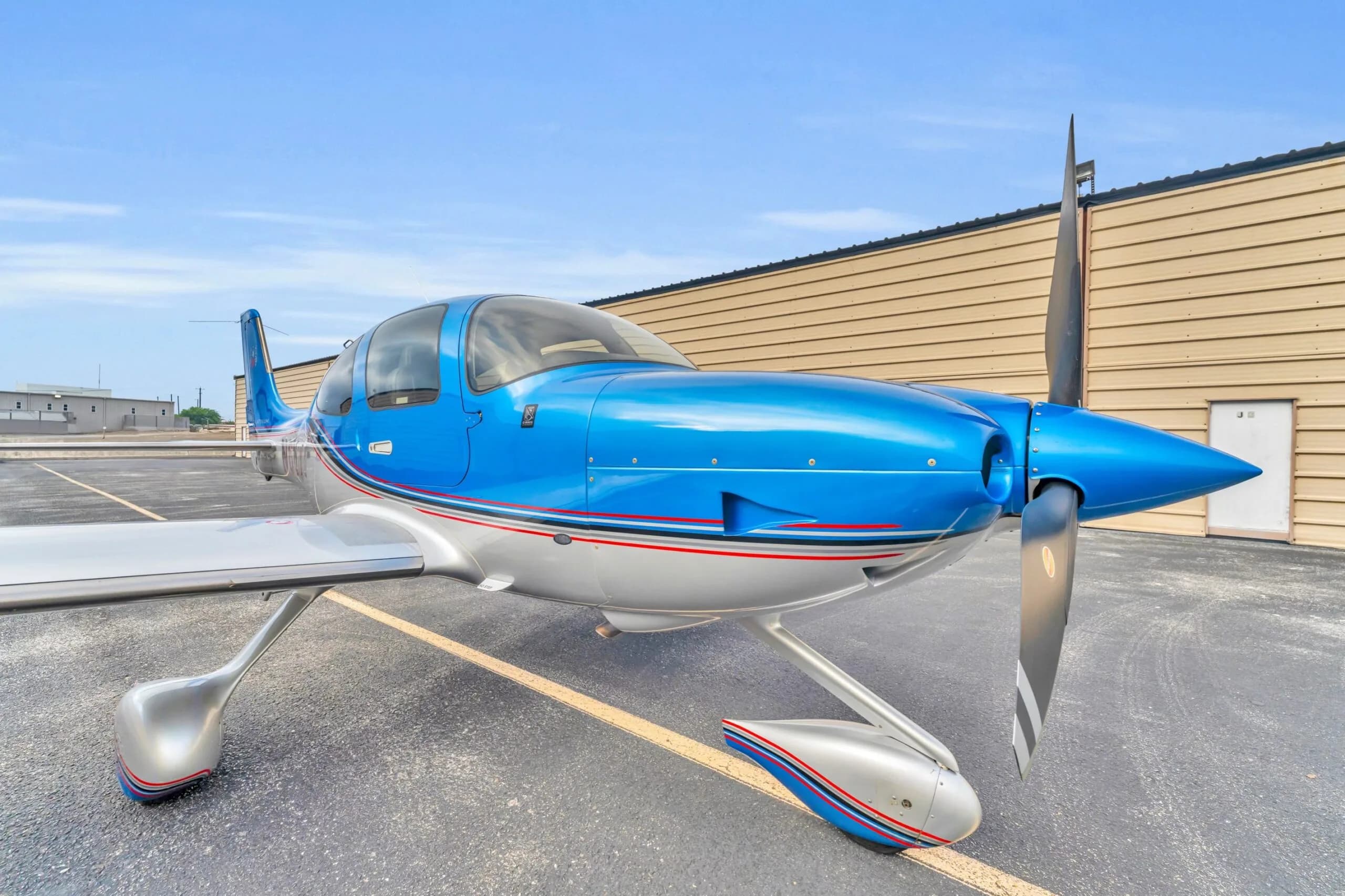 A close-up front-right view of the propeller and nose of the blue and silver Cirrus SR22T GTS aircraft N66TM.