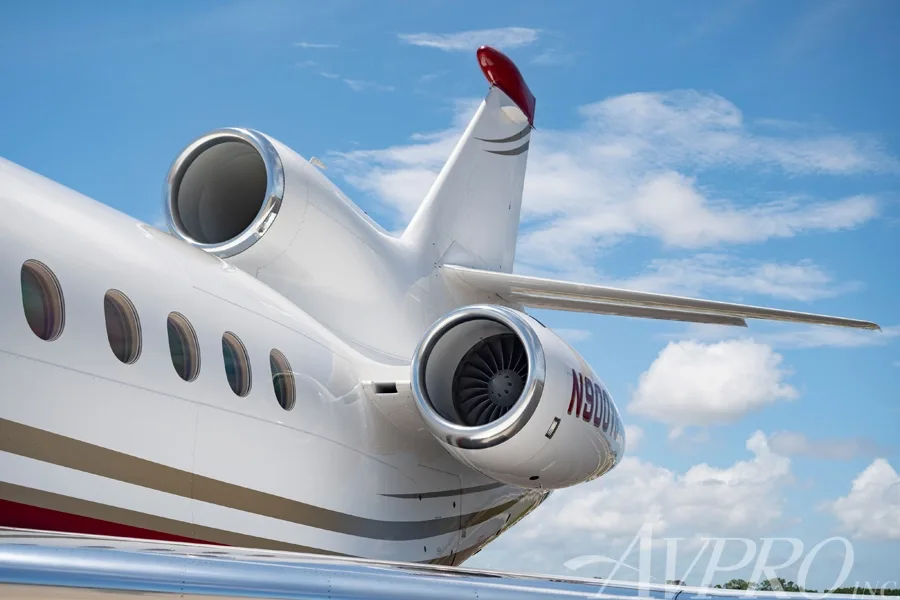 Close-up view of the tail and two rear-mounted engines of a white and red Dassault Falcon 900EX.
