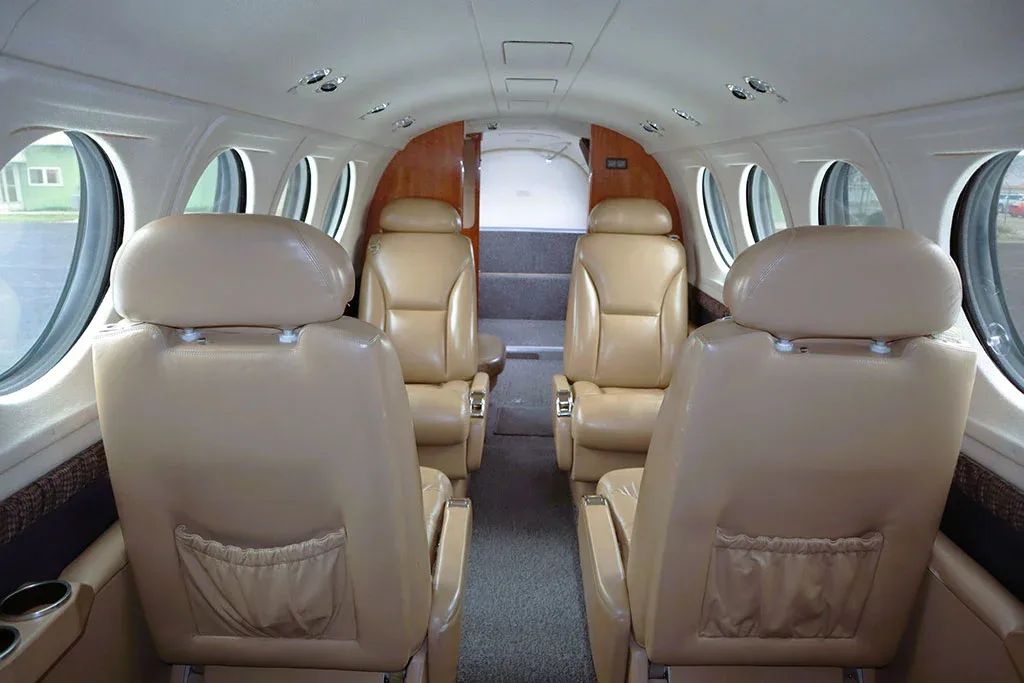 The interior cabin of an aircraft showing tan leather seats and a rear view towards the aft cabin.