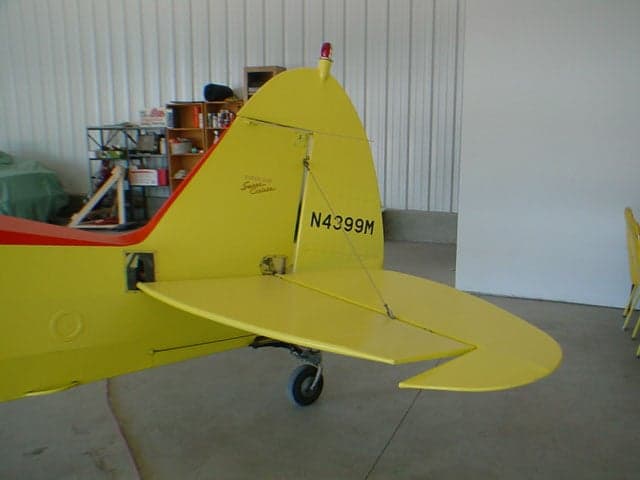 The yellow tail section of a Piper Super Cub aircraft with registration N4399M visible.