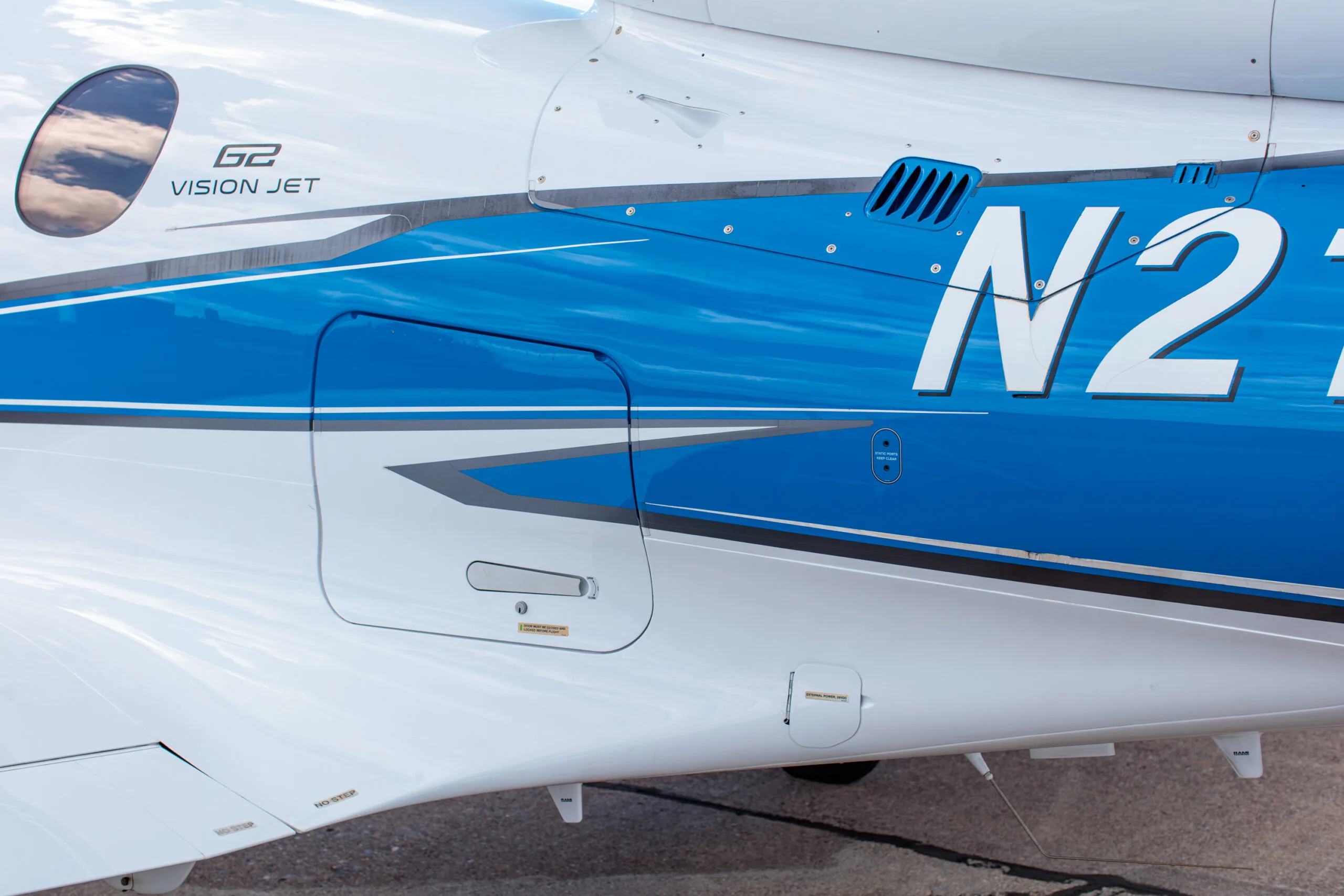 Close-up of the fuselage of the Cirrus Vision Jet (N218HP) showing the G2 Vision Jet logo and blue stripe.