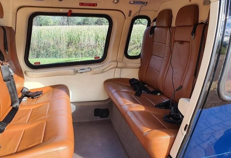 The interior of the helicopter features tan leather seats and a view out the window.