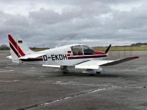 Side view of a white and red aircraft with German flag on the tail, parked on the tarmac.