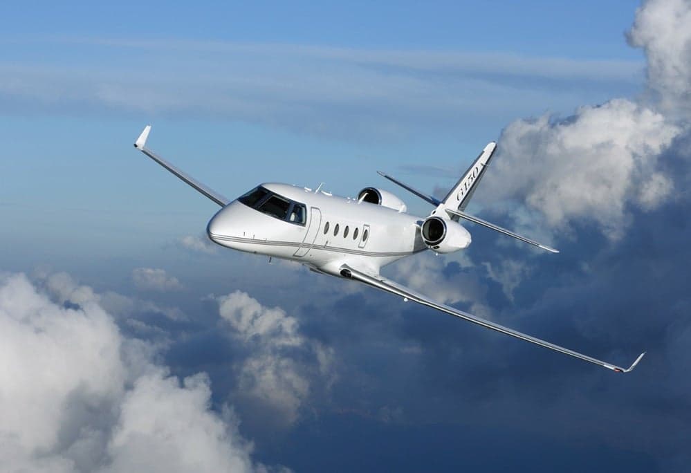 A Gulfstream G150 in flight against a cloudy sky.
