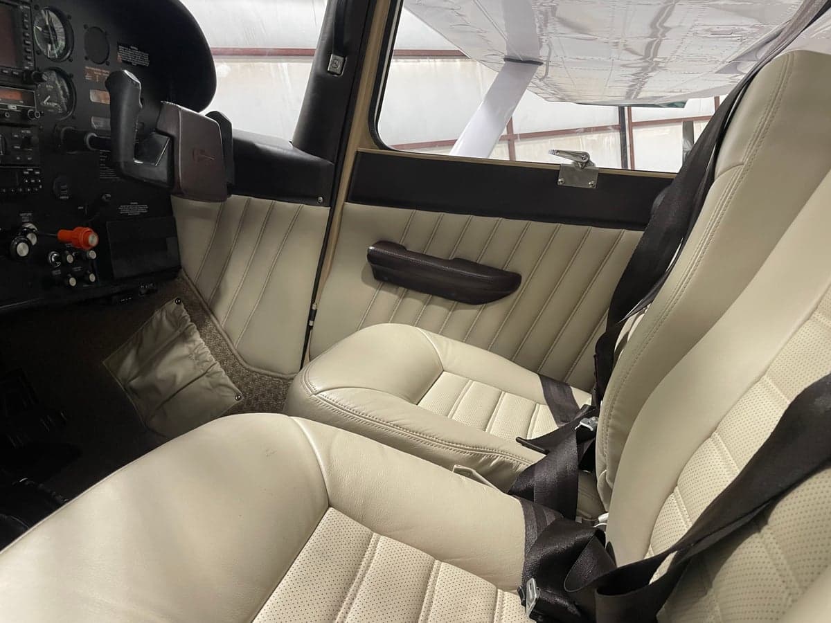Front seats of the Cessna 185 Skywagon with light colored upholstery.