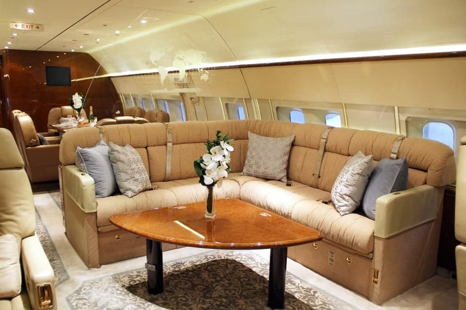 A spacious aircraft interior with a large sofa and elegant decor.