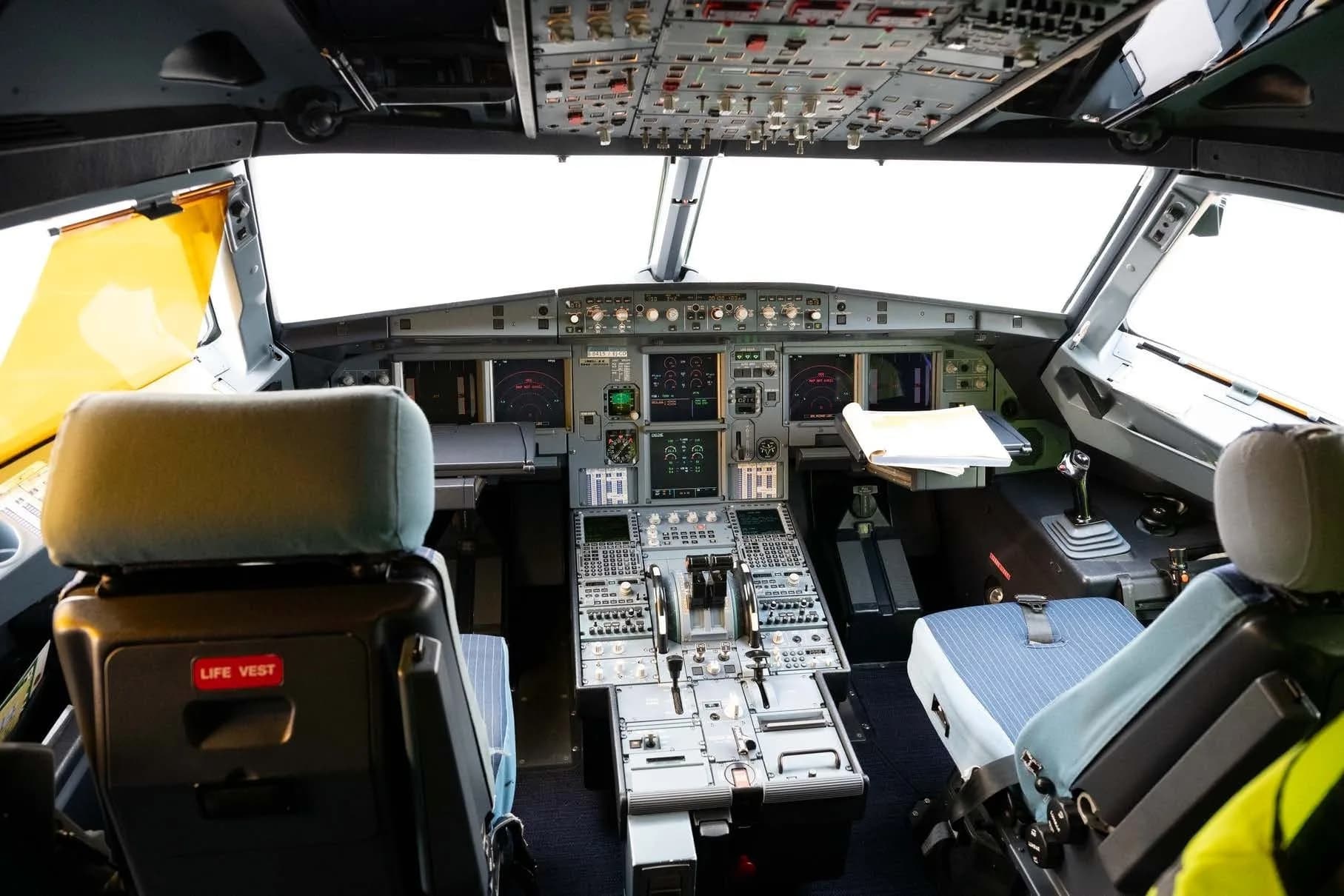 The cockpit of an Airbus A320 family aircraft with its instrument panel and pilot seats.