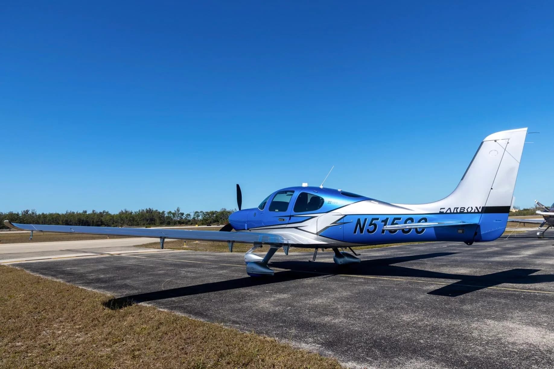 A three-quarter front view of a blue and silver Cirrus SR22 aircraft (N515SC) parked on an airfield.