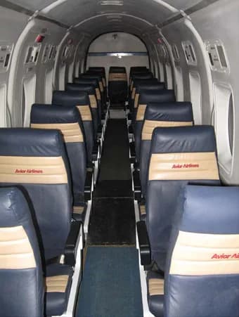 A view down the aisle of an aircraft cabin with blue seats.