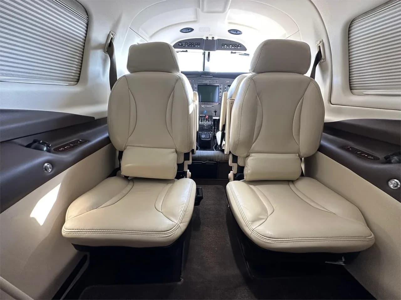 The cabin interior of the Piper M350 aircraft, showing two light-colored leather seats facing the cockpit.