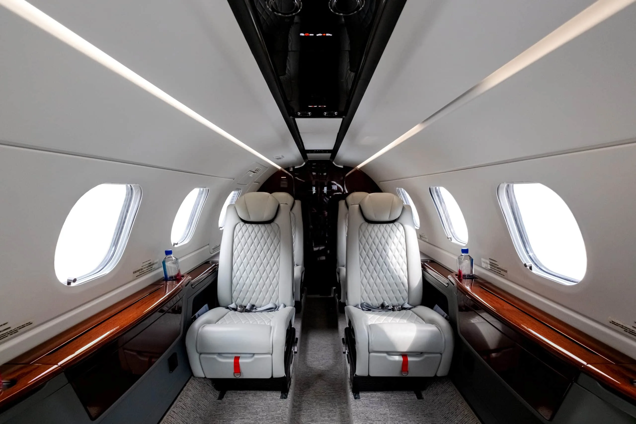 View down the aisle of the aircraft cabin with white leather seats.