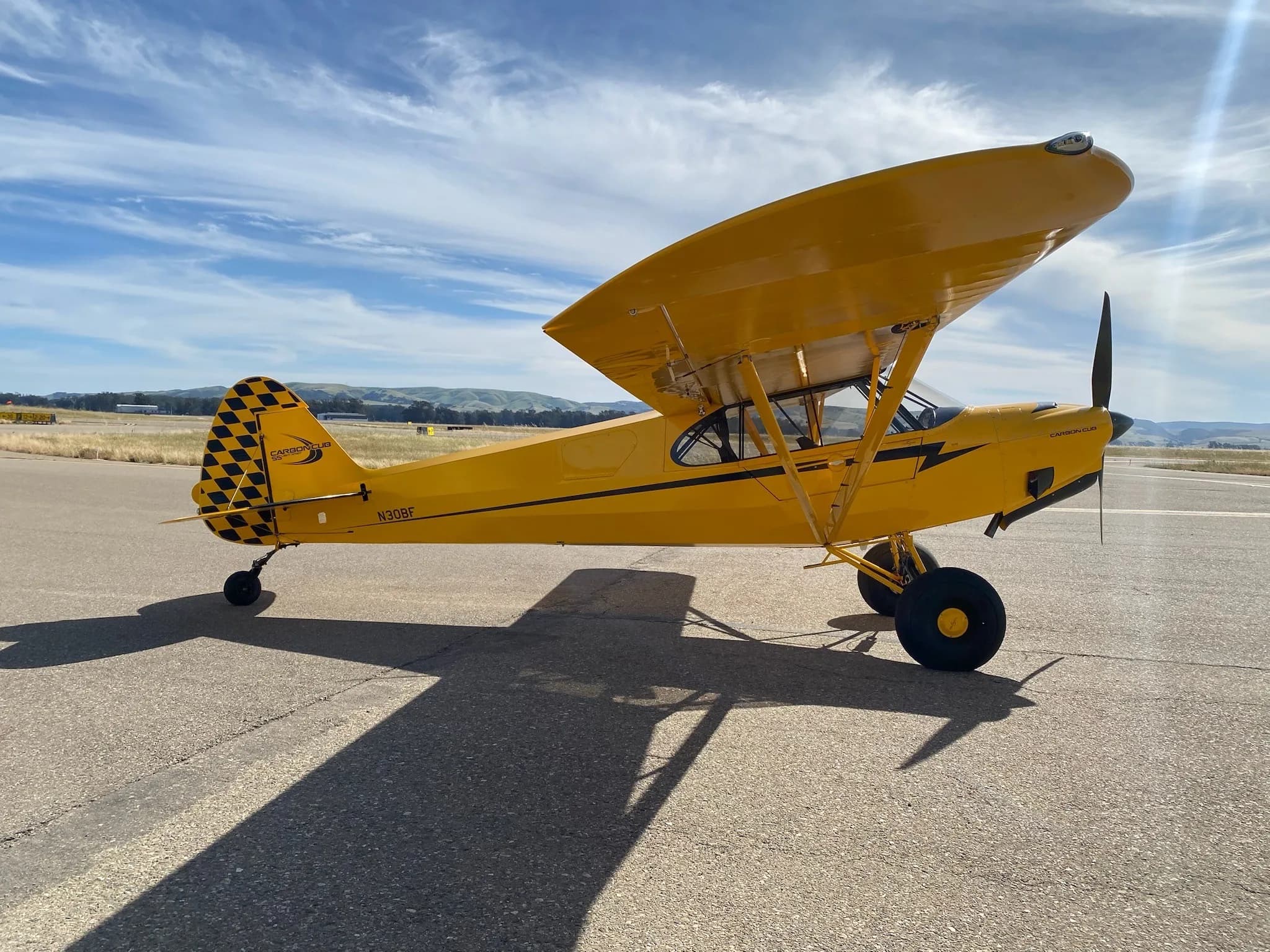 A yellow Carbon Cub aircraft with registration N30BF is parked on the tarmac.