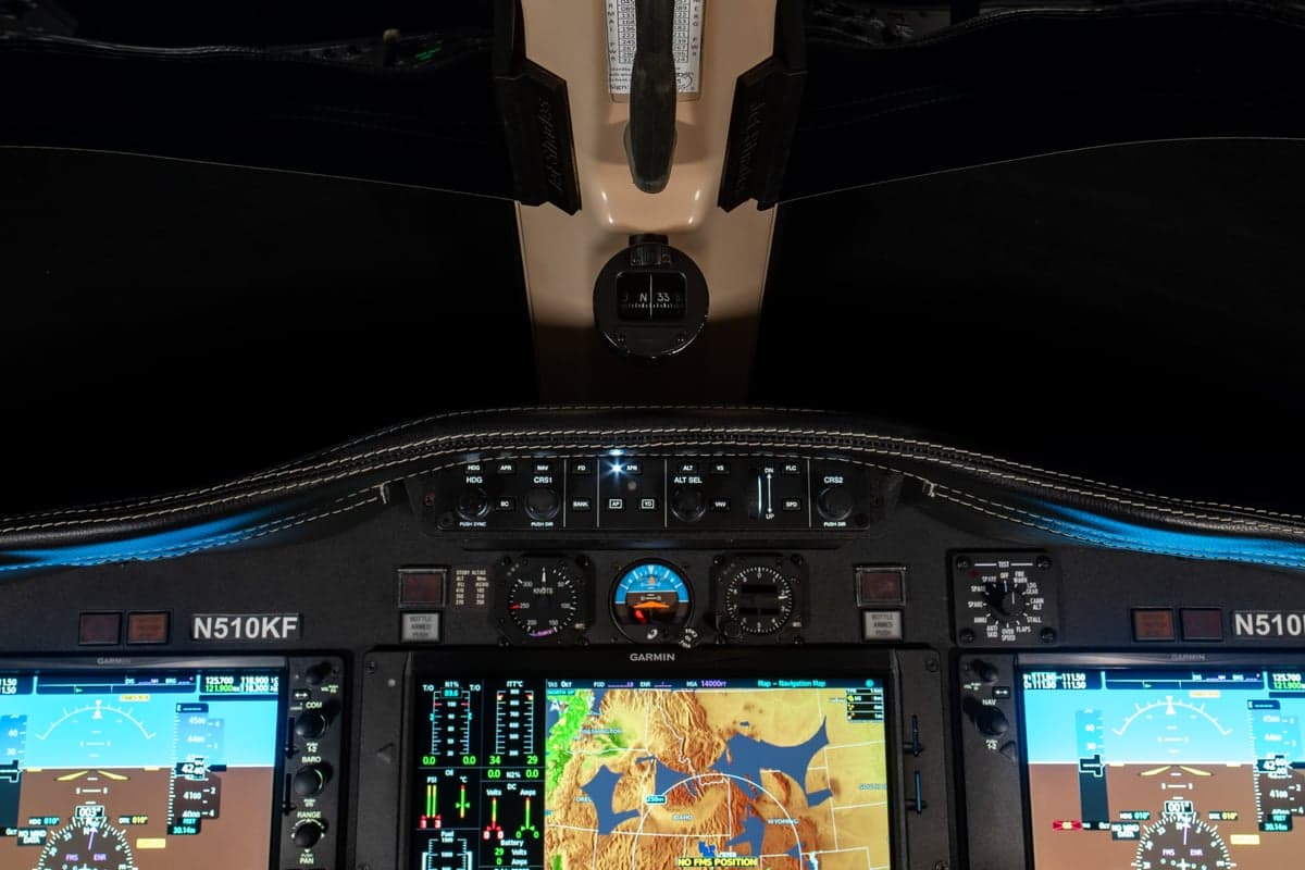 An overhead view of the Cessna Citation M2 cockpit, showing the instrument panel with multiple Garmin displays and overhead controls.