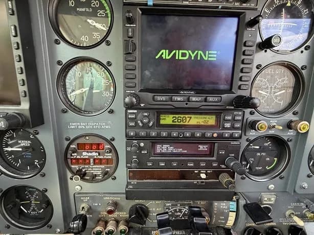 Close-up view of an aircraft instrument panel with analog gauges and digital displays, including an Avidyne screen.