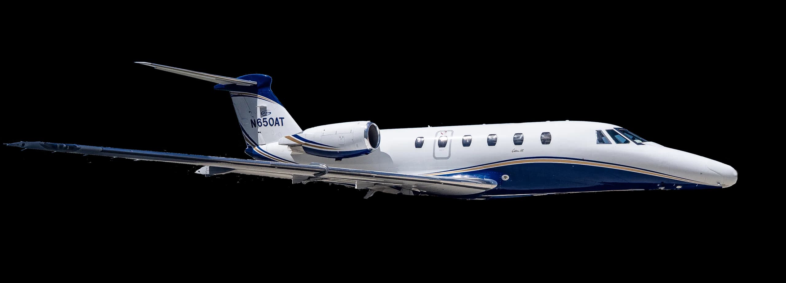 Side view of a white and blue jet with registration N650AT against a black background.