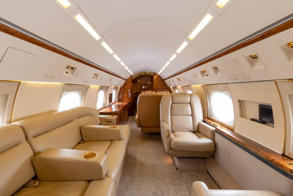 A view of the business jet's interior cabin featuring a beige leather sofa and individual seats.