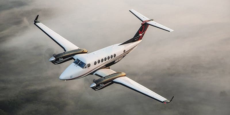 A King Air aircraft in flight above the clouds.