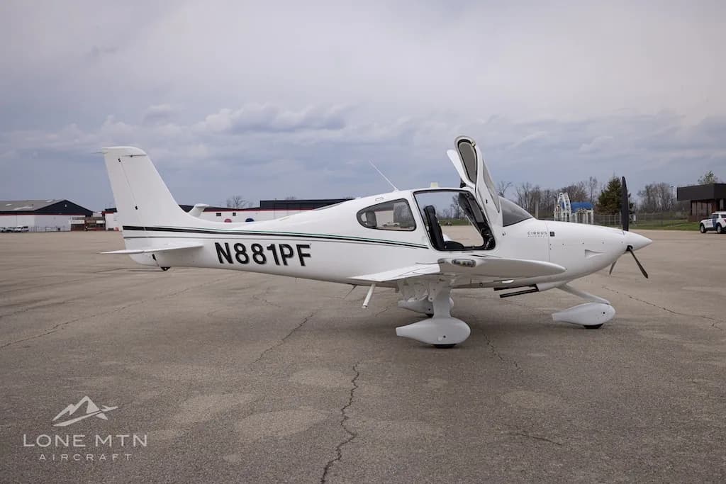 A white Cirrus SR22 aircraft with N881PF registration and open doors, parked on an asphalt ramp.