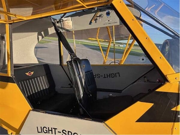 Interior view of the two black seats and cabin area of the yellow Legend Cub aircraft.