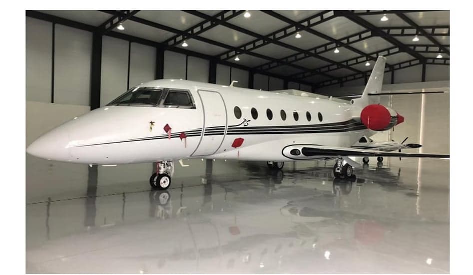 A white and black aircraft is parked inside a hangar.