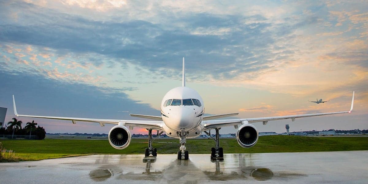 Front view of a white and navy Boeing 757 business jet parked on the tarmac.
