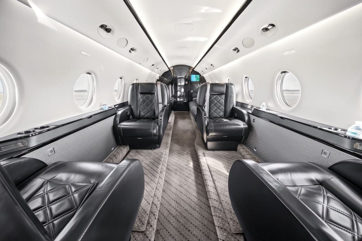 A view of the interior of the aircraft, showing the leather seats and carpeted floor.