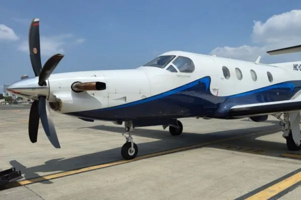 A close-up view of the front fuselage and propeller of a white and blue Pilatus PC-12 aircraft.