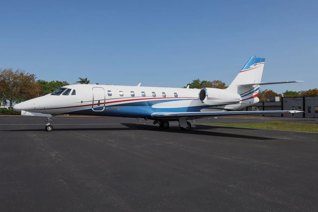 Side view of a white jet with blue and red accents parked on the tarmac.