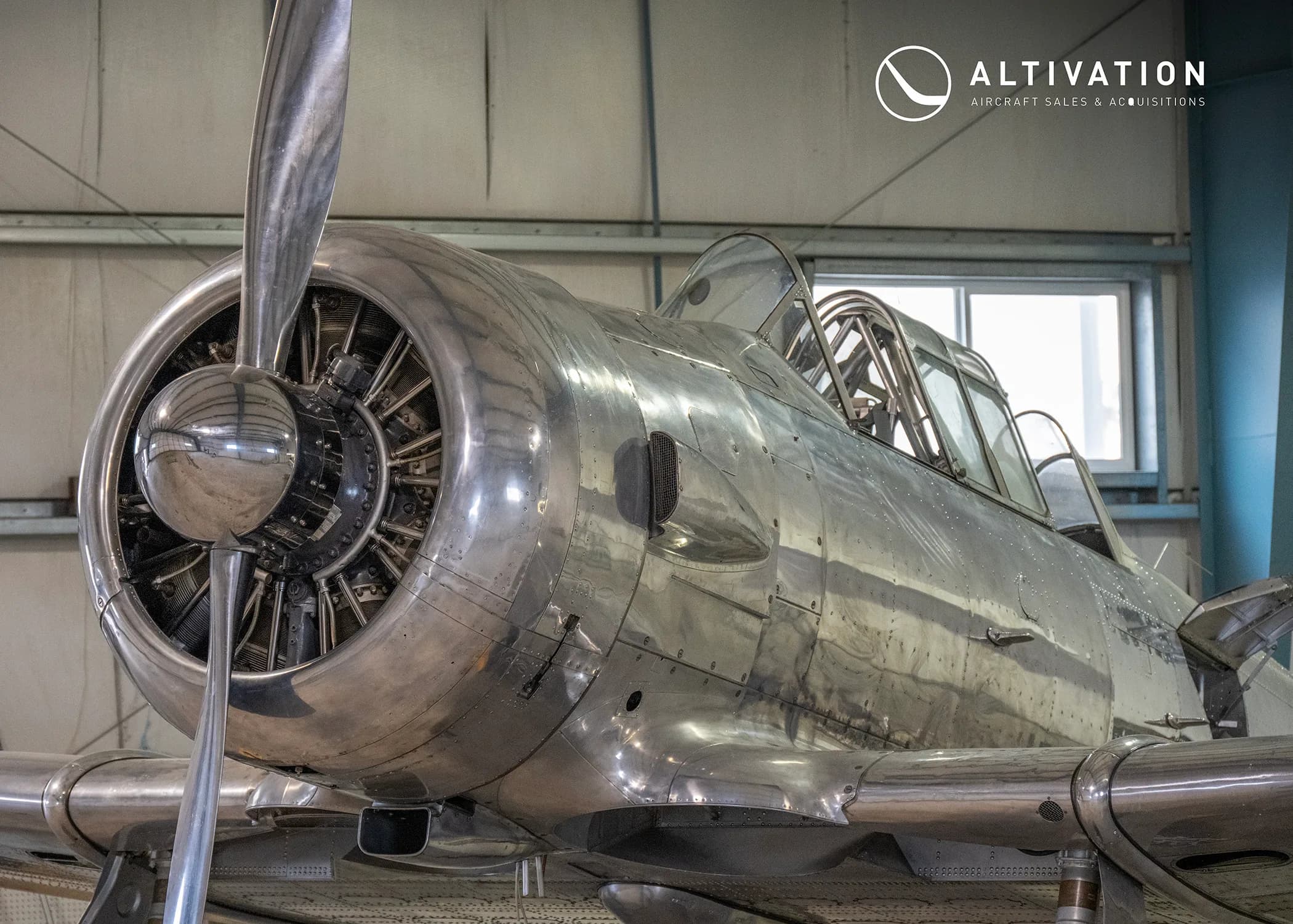 Close up of the propeller and engine of a silver aircraft.