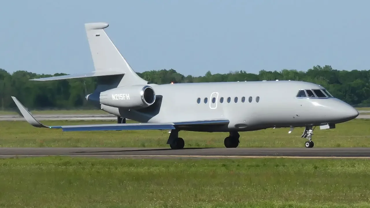 A Dassault Falcon 2000S business jet, registration N215FH, in matte grey, taxiing on an airfield under a clear blue sky.