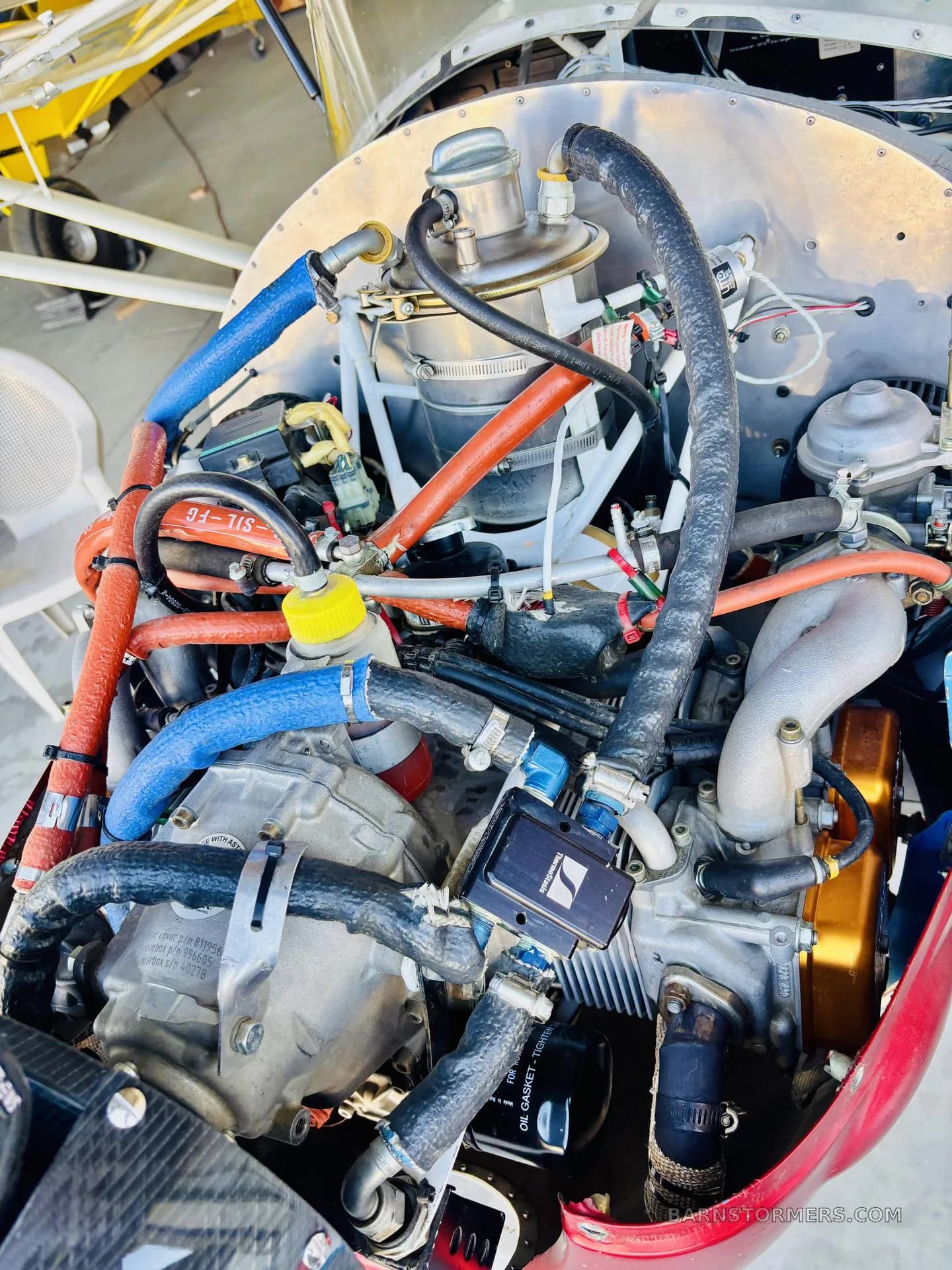 A detailed view of an aircraft engine compartment, showing various hoses, wires, and mechanical components.