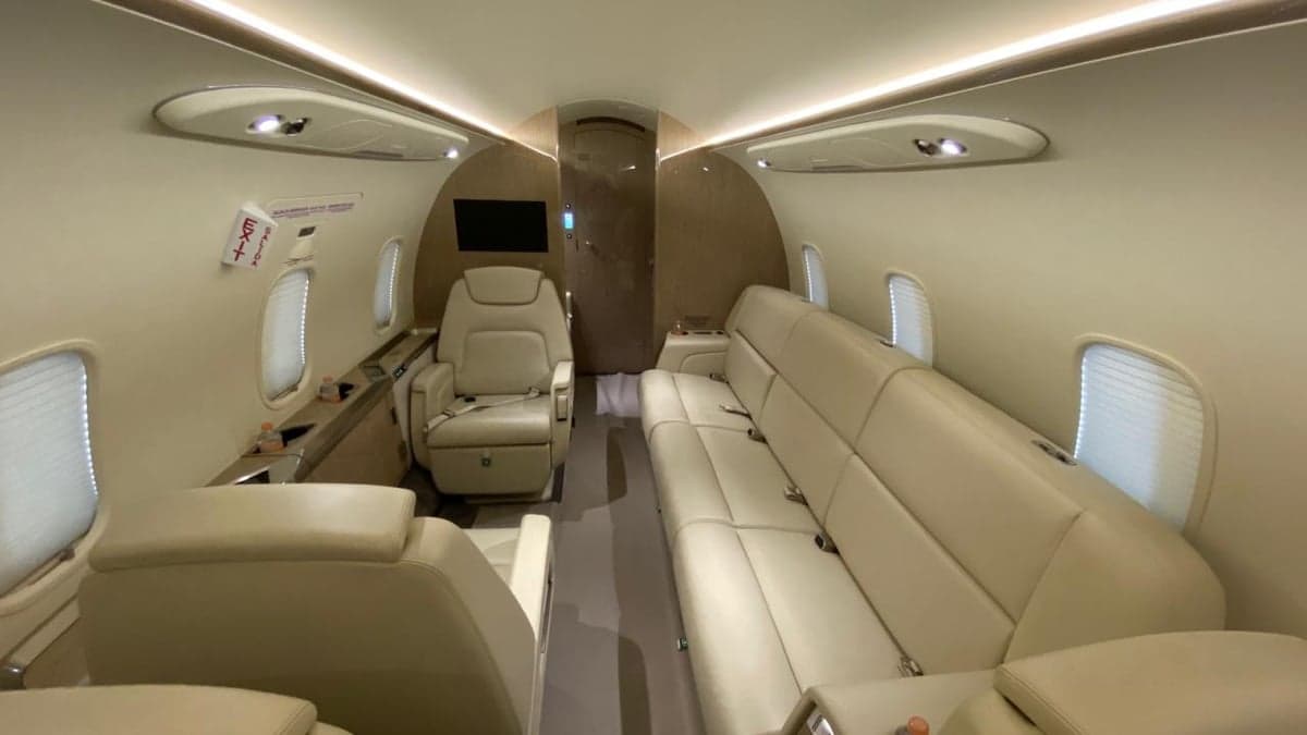 View of the aircraft cabin with cream-colored leather seats and a sofa.