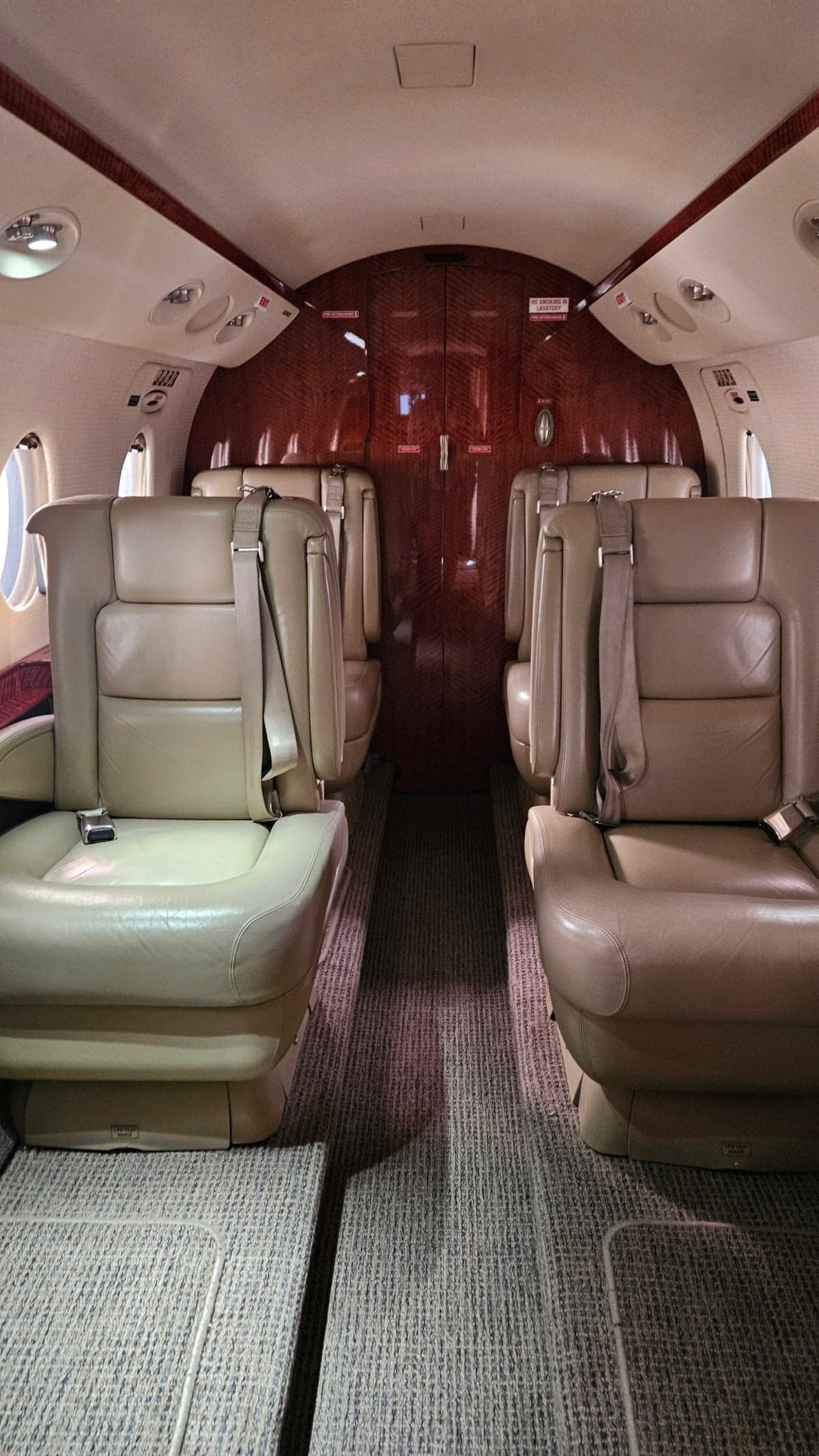 A view of the aircraft's tan leather cabin seats and wood-paneled interior.