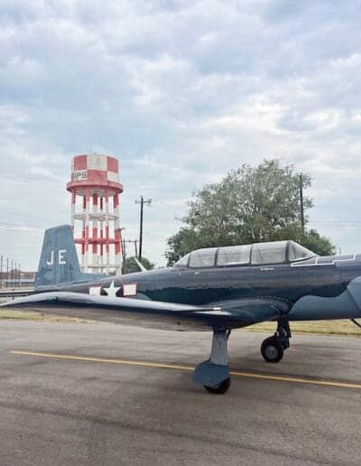 Side view of the gray N700YK aircraft with a water tower in the background.