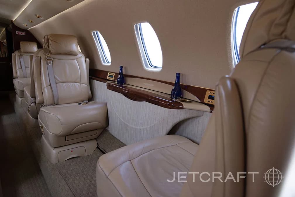 The interior of a jet with leather seats and a side table.