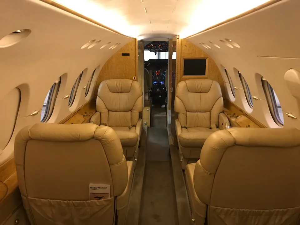 View of the aircraft's interior with tan leather seats and wood trim.
