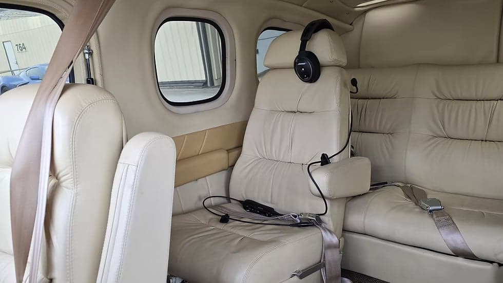 The interior of the aircraft features cream-colored leather seats and a headset.